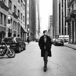 man walking down the centre of an empty downtown street