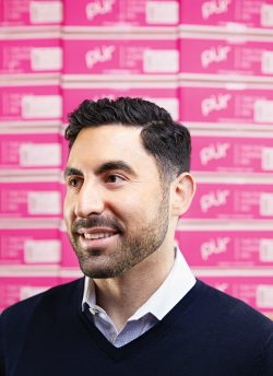 Portrait of Jay Klein smiling with boxes of Pur gum behind him