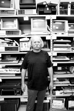 Zbigniew Stachniak standing in fron of shelves full of vintage computers