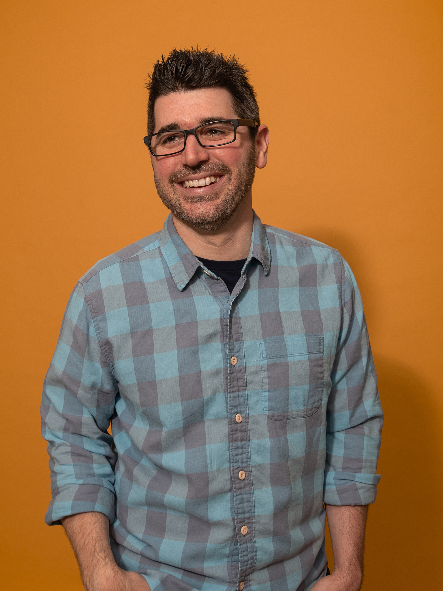 image of man in glasses and plaid shirt smiling