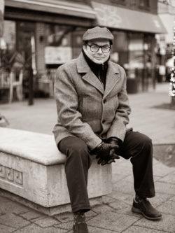 CHRIS DASSIOS seated on stone bench in Toronto's Greektown