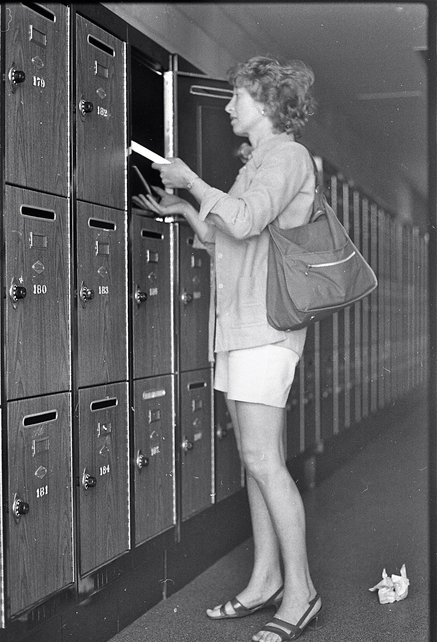 vintage black and white photograph of woman putting books into a locker 