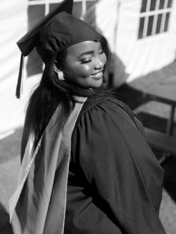 graduate in cap and gown looking over her shoulder smiling