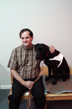 Ben Fulton, smiling, seated next to dog