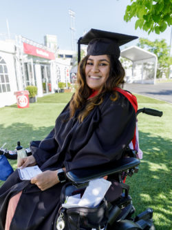 smiling woman grad in cap and gown in wheelchair