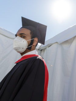 masked male grad in cap and gown