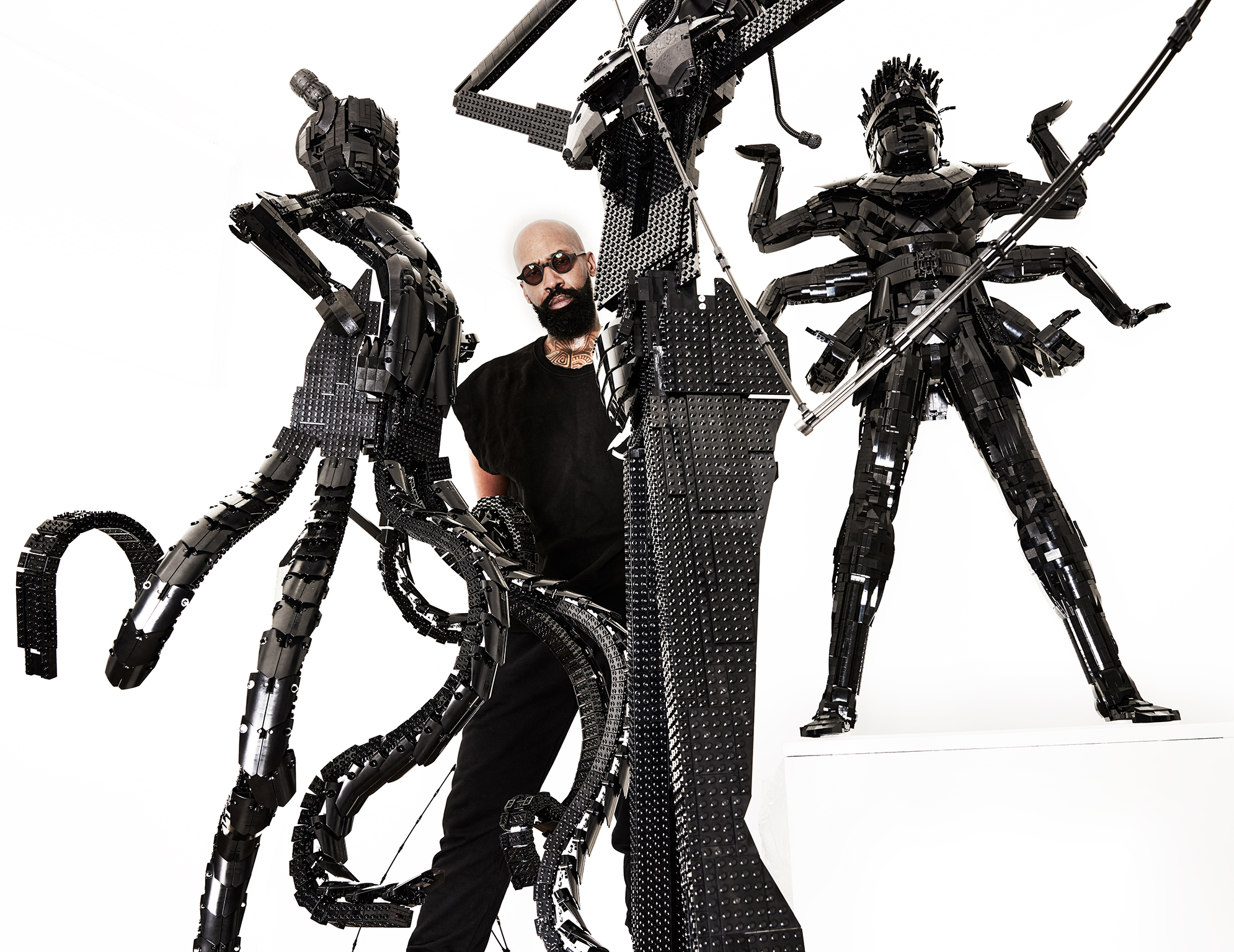 Ekow Nimako standing behind 2 of his sculptures with a third behind him
