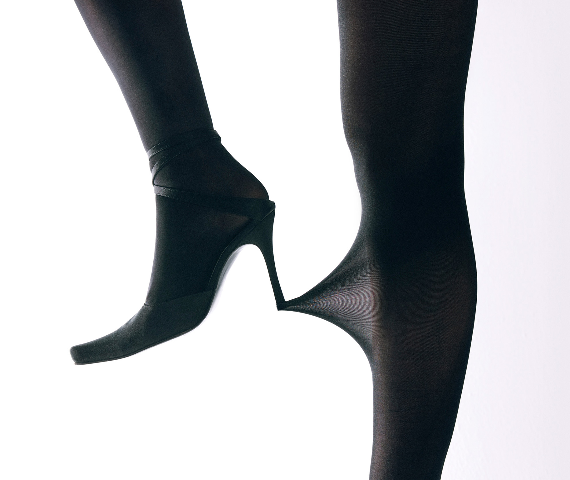 high heel shoe pulling on tights-covered leg