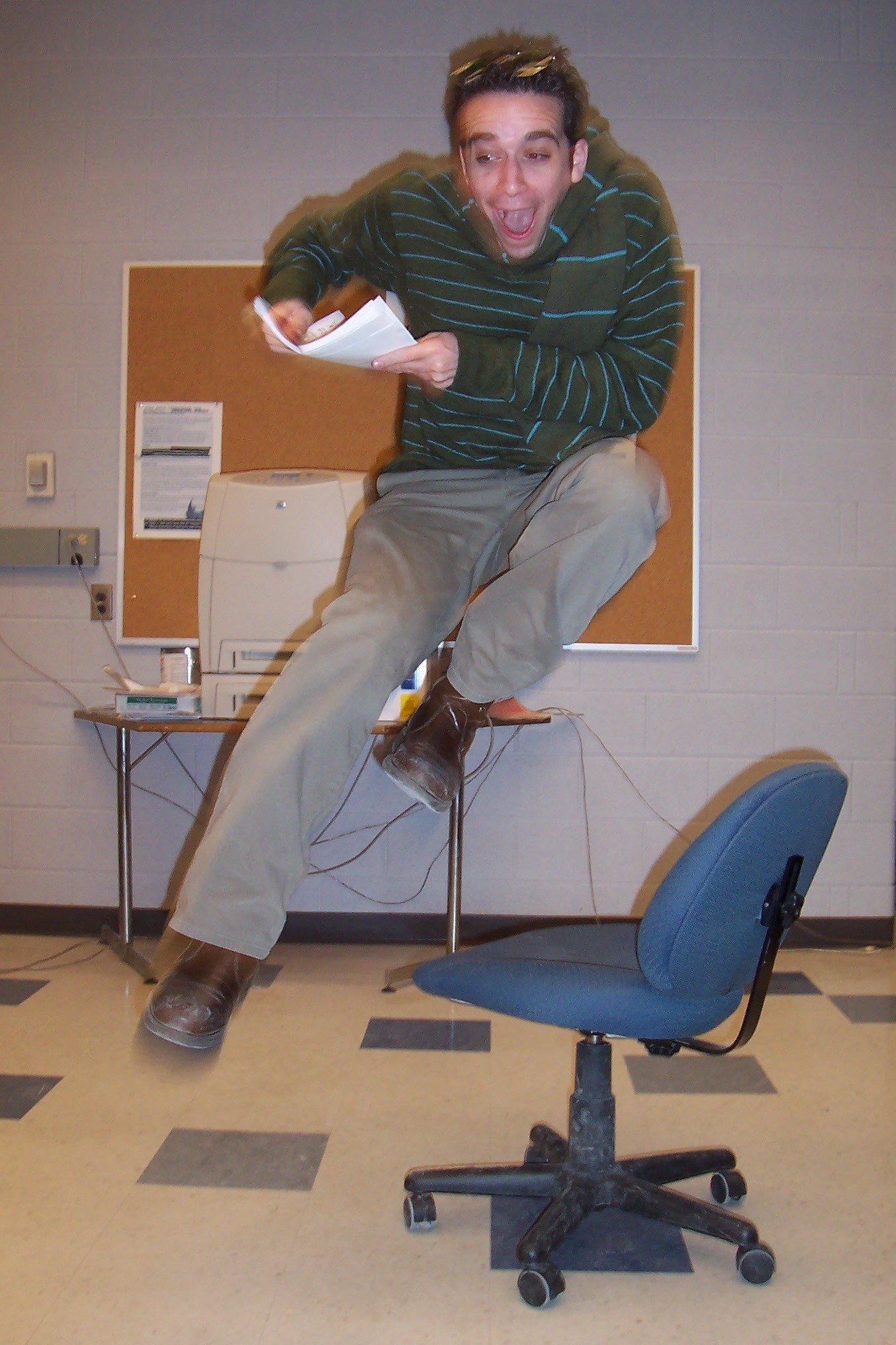 Ori Dagan, holding papers,  in mid-air jumping over a desk chair