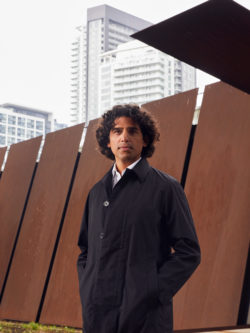 Usman Khan in front of wall at Toronto's Bentway under the Gardener Expressway, high-rise building in back